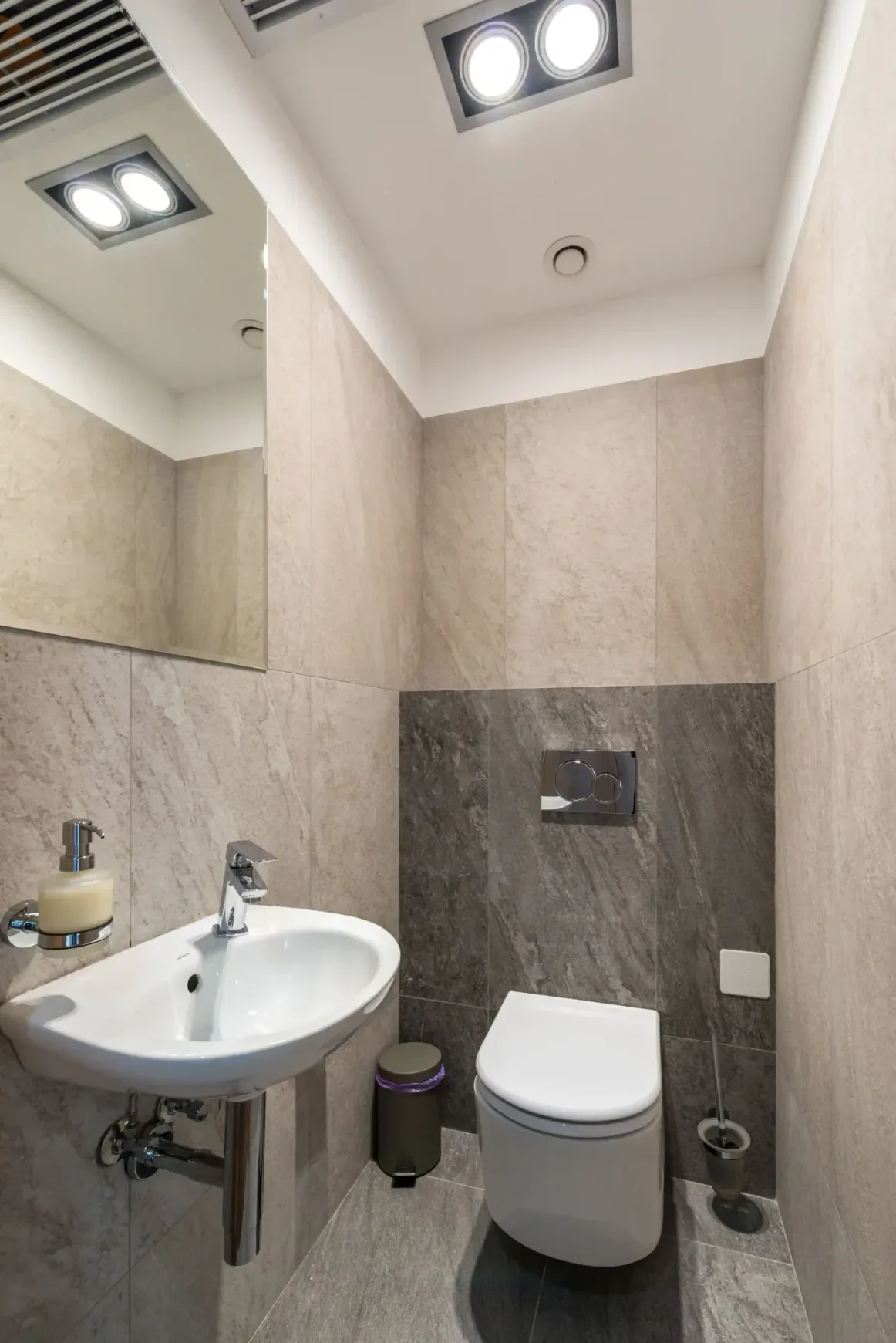 Small powder room with large-format beige stone-look wall tiles in a Carson home