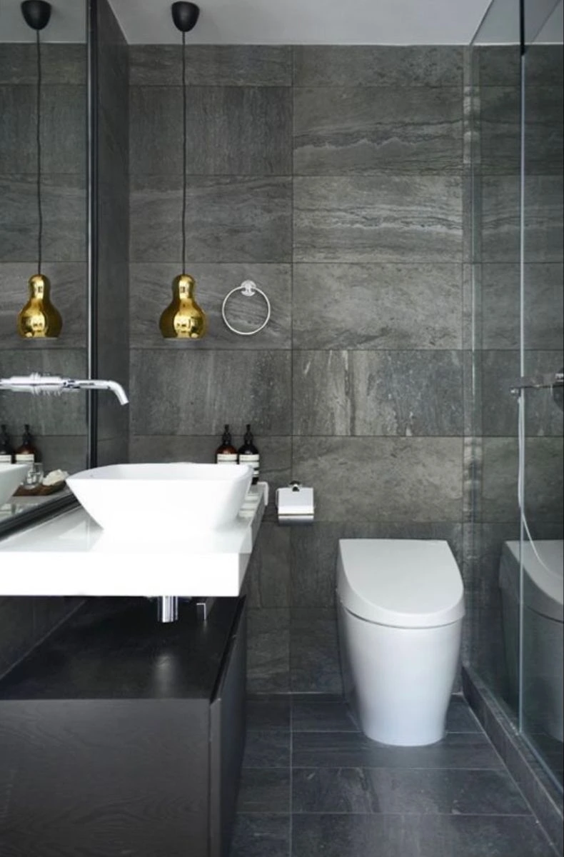 Sophisticated bathroom with floor-to-ceiling dark gray slate tiles and gold pendant lights