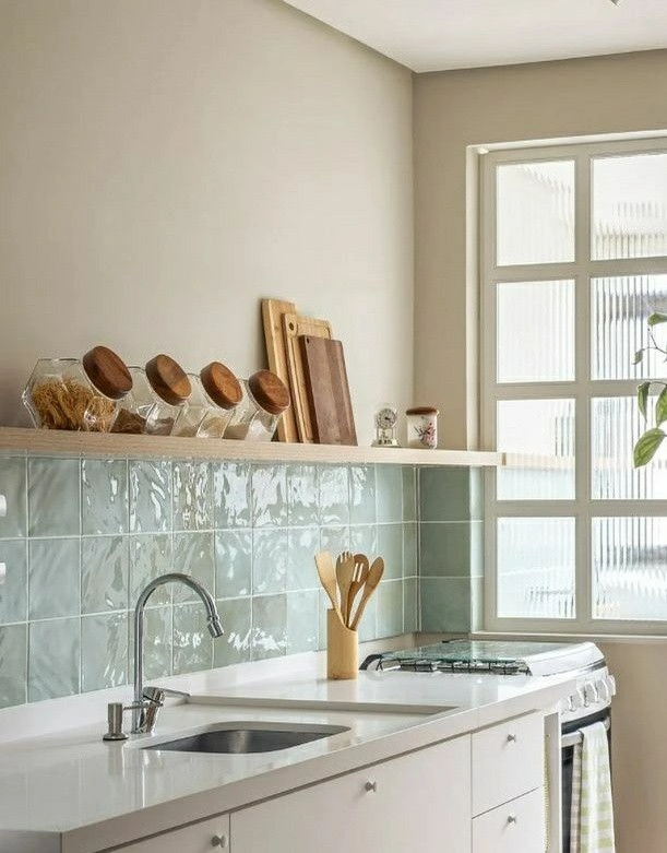 Bright kitchen with glossy sage green square tile backsplash and white countertops