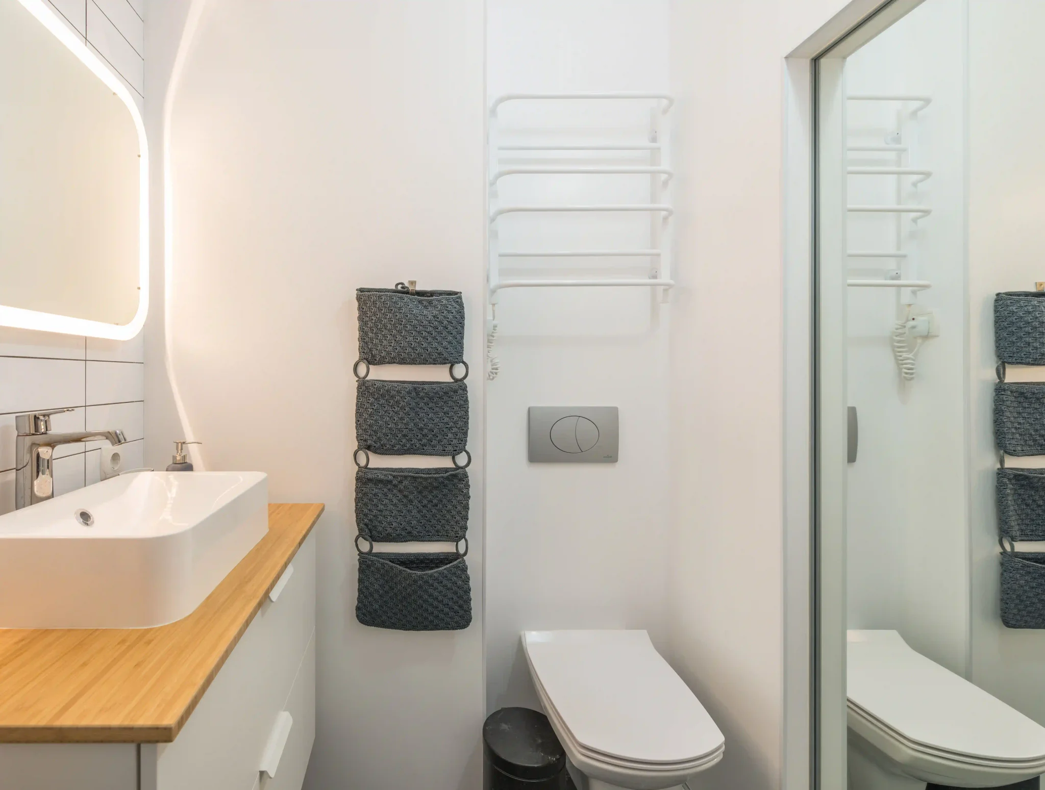 Compact white-tiled bathroom with wood vanity in Carson